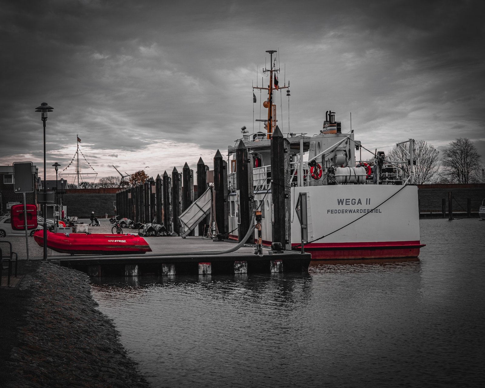 Hafenaufnahme der WEGA II in Fedderwardersiel mit rotem Rettungsboot im Vordergrund.